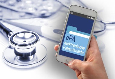 Das Bild zeigt eine Hand, die ein Smartphone hält. Auf dem Bildschirm des Smartphones ist eine Anwendung mit der Aufschrift „ePA – elektronische Patientenakte“ zu sehen. Im Hintergrund liegen medizinische Utensilien, wie ein Stethoskop und Tablettenblister. Das Bild zeigt eine Hand, die ein Smartphone hält. Auf dem Bildschirm des Smartphones ist eine Anwendung mit der Aufschrift „ePA – elektronische Patientenakte“ zu sehen. Im Hintergrund liegen medizinische Utensilien, wie ein Stethoskop und Tablettenblister.